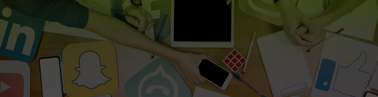 Na stole leżą: ikona Snaptchata, whatsupa, tablet i telefon wraz z zeszytem i długopisami